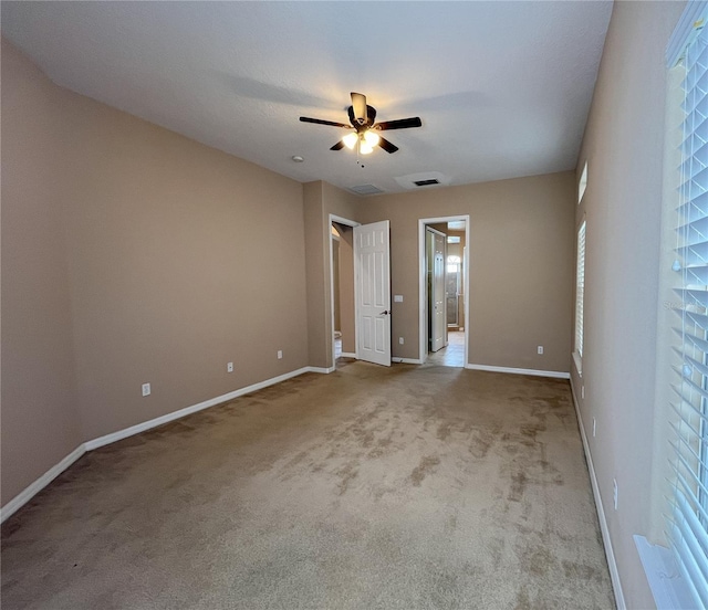 unfurnished bedroom with ceiling fan, light carpet, and multiple windows