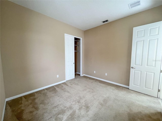 unfurnished bedroom with light colored carpet and a textured ceiling