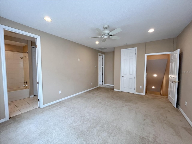 unfurnished bedroom featuring light carpet, ensuite bathroom, and ceiling fan