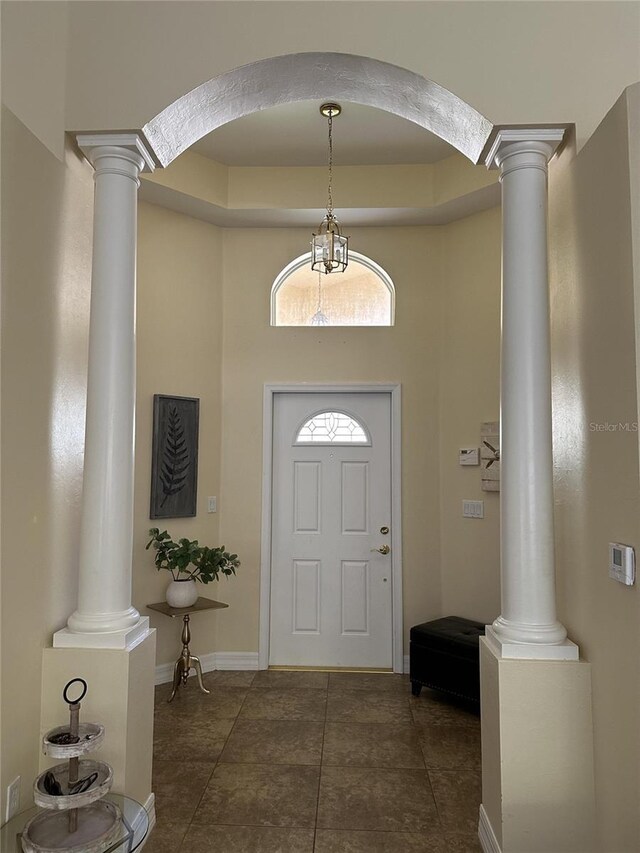 foyer entrance with dark tile patterned floors and decorative columns