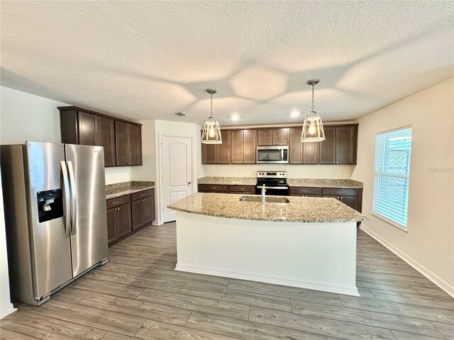 kitchen with appliances with stainless steel finishes, light stone countertops, dark wood-type flooring, and hanging light fixtures