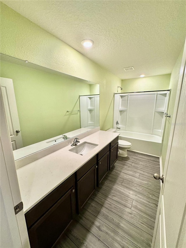 full bathroom featuring a textured ceiling, vanity, hardwood / wood-style floors, toilet, and bathtub / shower combination