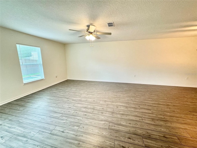 empty room featuring hardwood / wood-style floors, ceiling fan, and a textured ceiling