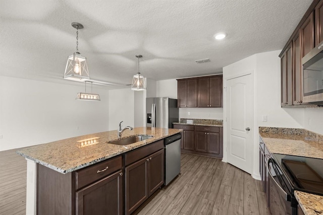 8 Slipper Flower Path E, Palm Coast, FL 32164 - kitchen featuring stainless steel appliances, a sink, light wood-style flooring, dark brown cabinets, and a textured ceiling