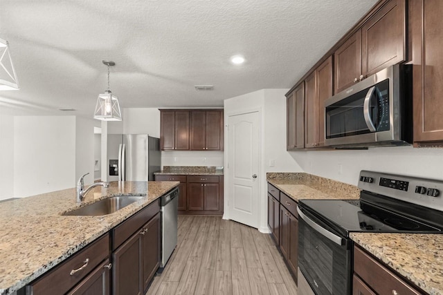 8 Slipper Flower Path E, Palm Coast, FL 32164 - kitchen featuring appliances with stainless steel finishes, a sink, light wood-type flooring, dark brown cabinetry, and light stone counters
