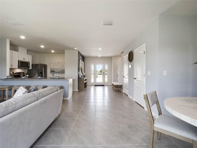 living room with sink, light tile patterned flooring, and french doors