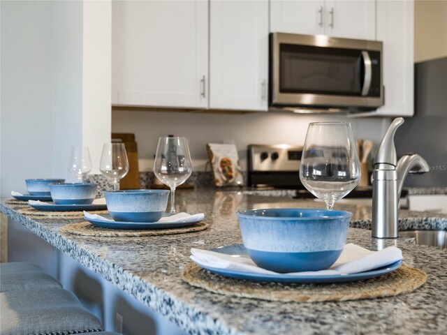 kitchen with light stone counters and white cabinetry