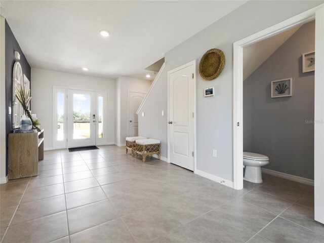 tiled foyer entrance featuring vaulted ceiling