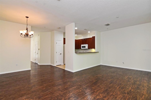 unfurnished living room with a textured ceiling, an inviting chandelier, and wood-type flooring