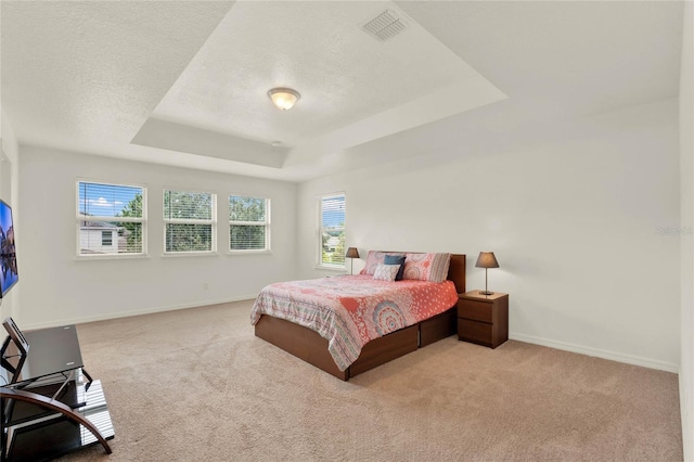 carpeted bedroom with baseboards, visible vents, a tray ceiling, and a textured ceiling