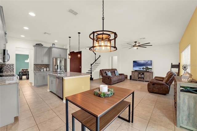 kitchen featuring light tile patterned floors, visible vents, a kitchen island with sink, stainless steel appliances, and gray cabinetry