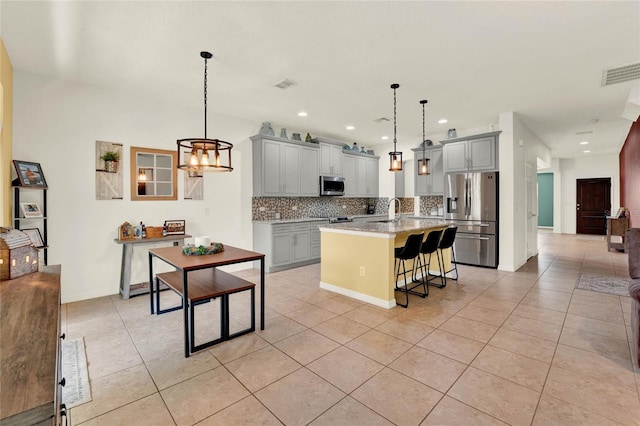 kitchen with stainless steel appliances, gray cabinets, visible vents, and backsplash