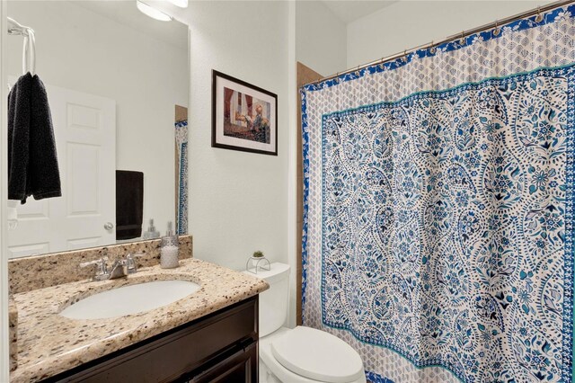 bathroom with curtained shower, vanity, and toilet