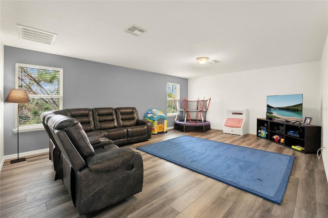 living room with visible vents, baseboards, and wood finished floors