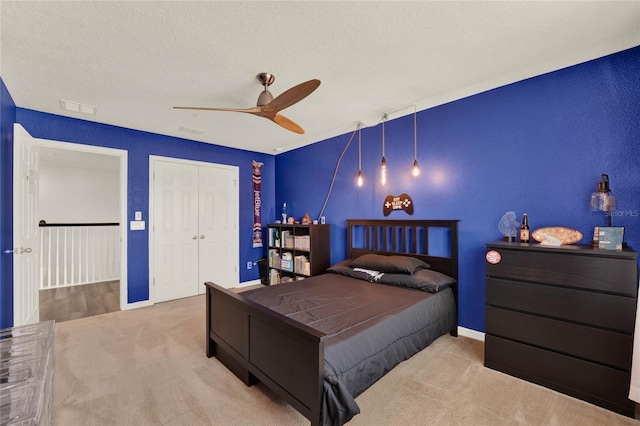 bedroom featuring carpet floors, a closet, visible vents, ceiling fan, and a textured ceiling