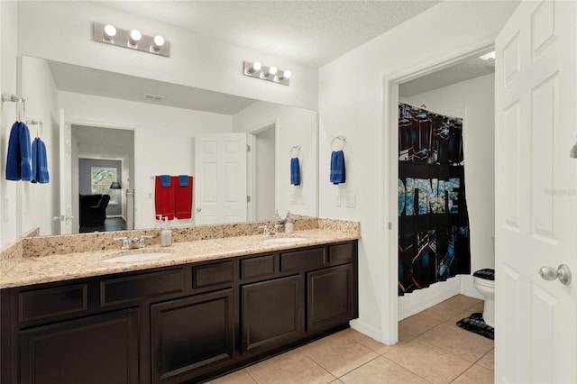 bathroom featuring tile patterned flooring, a sink, a textured ceiling, and double vanity