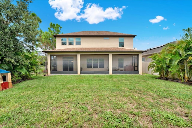 rear view of property featuring a sunroom, a yard, fence, and stucco siding