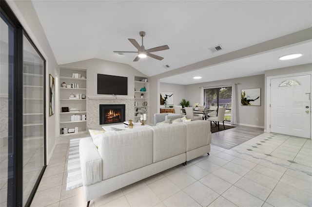 living room with ceiling fan, lofted ceiling, built in features, and light tile patterned floors