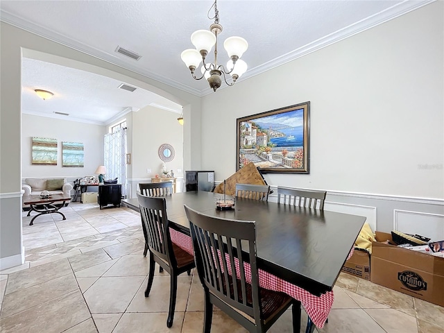 tiled dining space featuring a notable chandelier, ornamental molding, and a textured ceiling