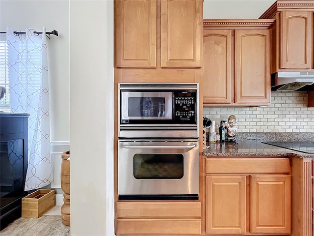 kitchen with decorative backsplash, dark stone countertops, appliances with stainless steel finishes, and light brown cabinetry