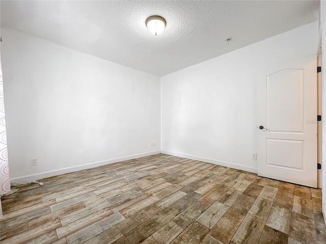 spare room with a textured ceiling and light hardwood / wood-style flooring