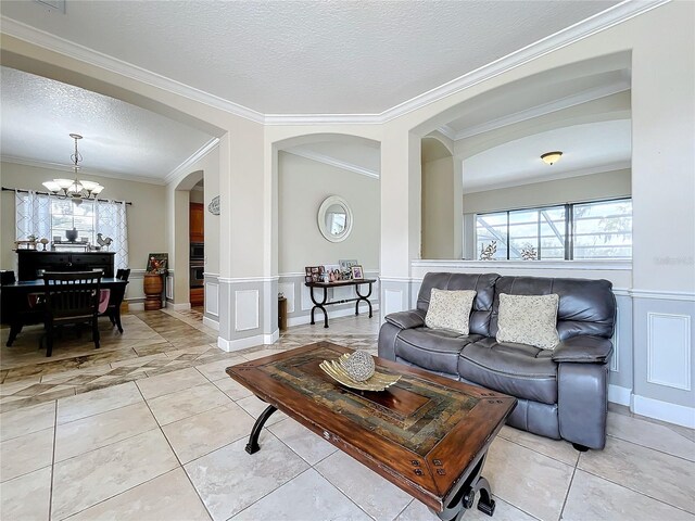 living room featuring an inviting chandelier, a textured ceiling, and ornamental molding