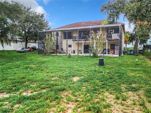 rear view of property with a lawn, a balcony, and a lanai