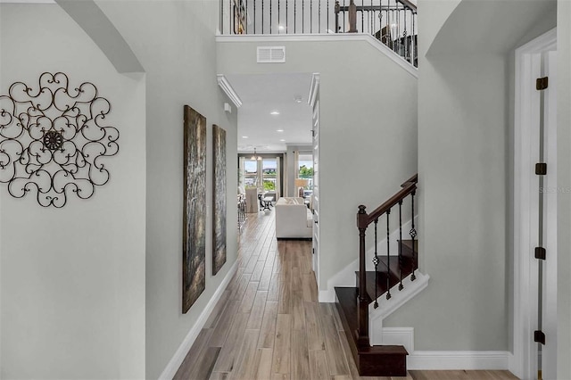 entrance foyer featuring baseboards, visible vents, wood finished floors, a high ceiling, and stairs