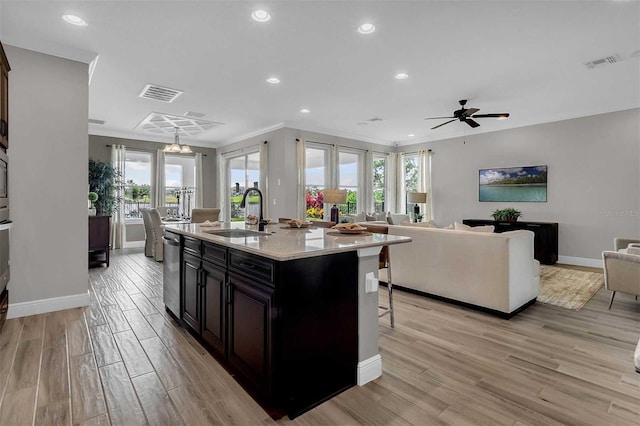 kitchen featuring stainless steel dishwasher, light wood-type flooring, a sink, and visible vents