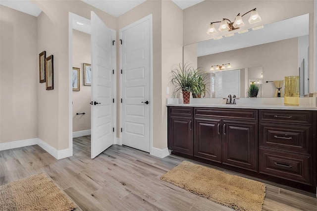 bathroom featuring baseboards, wood finished floors, and vanity