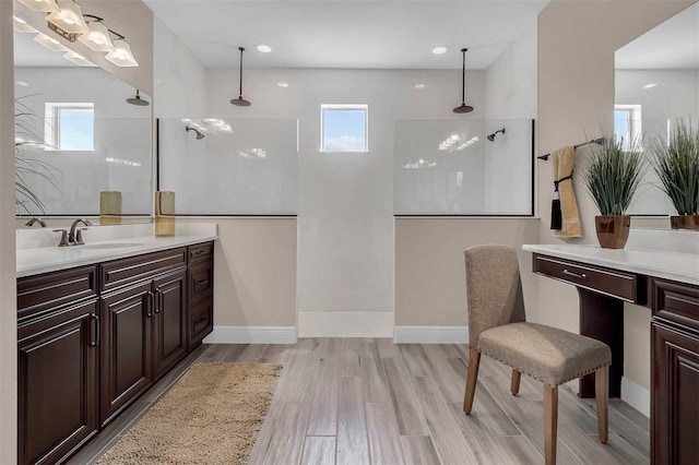 full bathroom with wood finished floors, vanity, baseboards, and a walk in shower