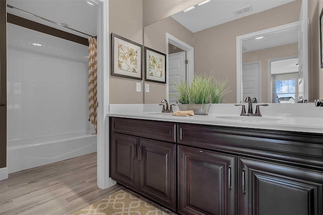 bathroom with double vanity, visible vents, a sink, and wood finished floors