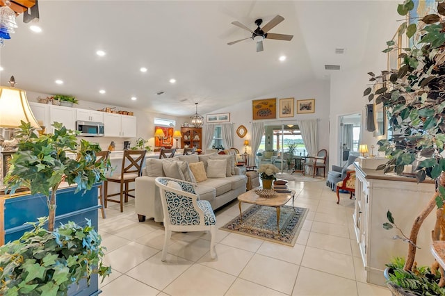 tiled living room with high vaulted ceiling and ceiling fan with notable chandelier