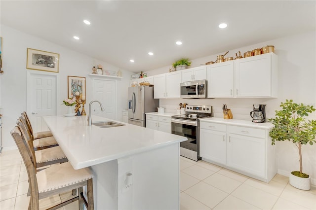 kitchen featuring lofted ceiling, white cabinets, sink, a breakfast bar area, and stainless steel appliances