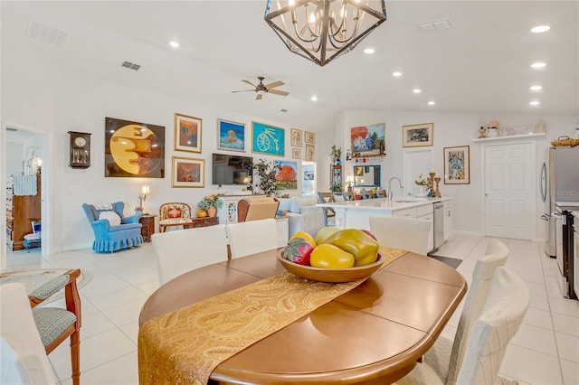 tiled dining space featuring ceiling fan with notable chandelier, vaulted ceiling, and sink