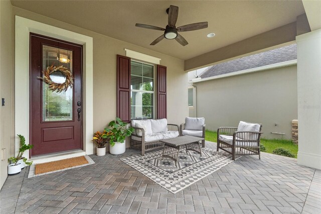 view of exterior entry with ceiling fan, outdoor lounge area, and a patio area