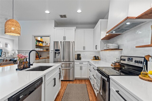 kitchen with light hardwood / wood-style floors, sink, white cabinets, hanging light fixtures, and appliances with stainless steel finishes