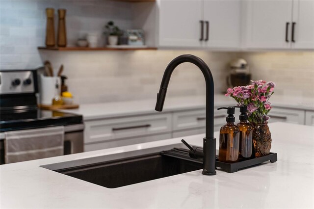 interior details featuring white cabinetry, range with electric cooktop, and tasteful backsplash