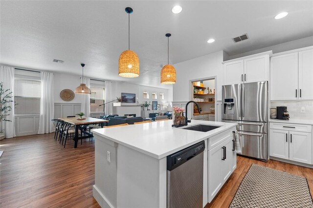 kitchen featuring stainless steel appliances, white cabinetry, and hanging light fixtures