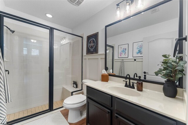 bathroom featuring vanity, toilet, a textured ceiling, a shower with shower door, and hardwood / wood-style floors