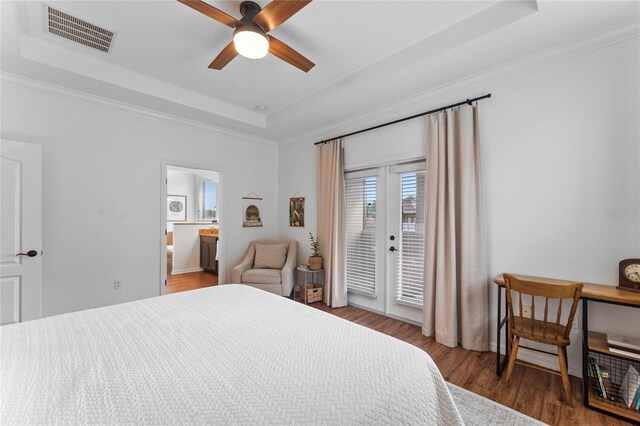 bedroom featuring a tray ceiling, dark wood-type flooring, ceiling fan, and access to exterior