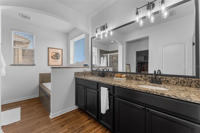 bathroom featuring plus walk in shower, wood-type flooring, plenty of natural light, and vanity