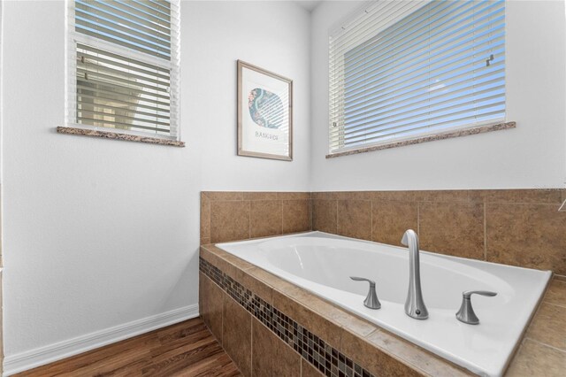 bathroom featuring hardwood / wood-style flooring and a relaxing tiled tub