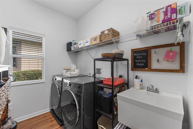 clothes washing area featuring washing machine and dryer, hardwood / wood-style floors, and sink