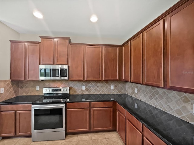 kitchen featuring backsplash, light tile patterned floors, appliances with stainless steel finishes, and dark stone counters