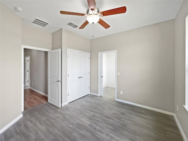 unfurnished bedroom featuring ceiling fan, a closet, and dark hardwood / wood-style flooring