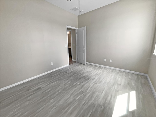 empty room with a high ceiling, ceiling fan, and hardwood / wood-style flooring