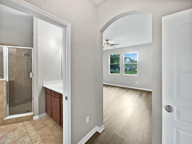 bathroom with a shower with shower door, ceiling fan, hardwood / wood-style floors, and vanity