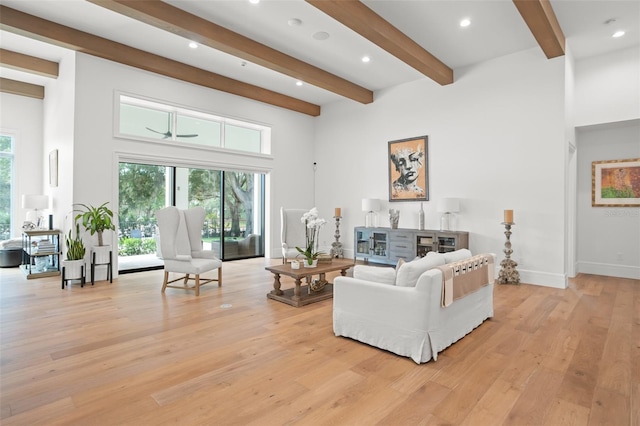 living room featuring a towering ceiling, beamed ceiling, and light hardwood / wood-style flooring