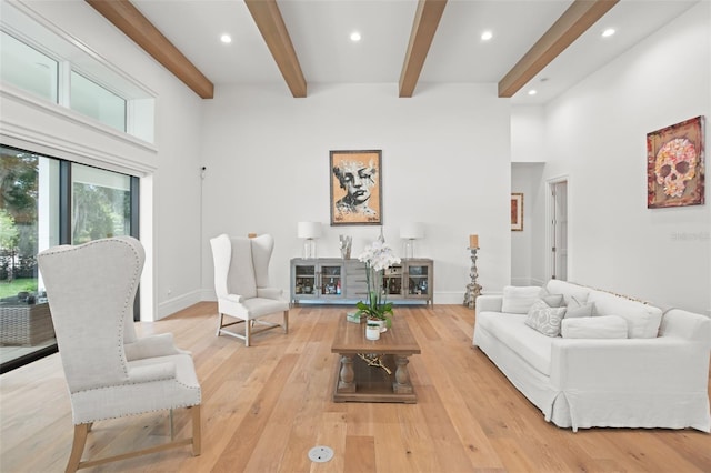 living room featuring a high ceiling, light hardwood / wood-style floors, and beamed ceiling